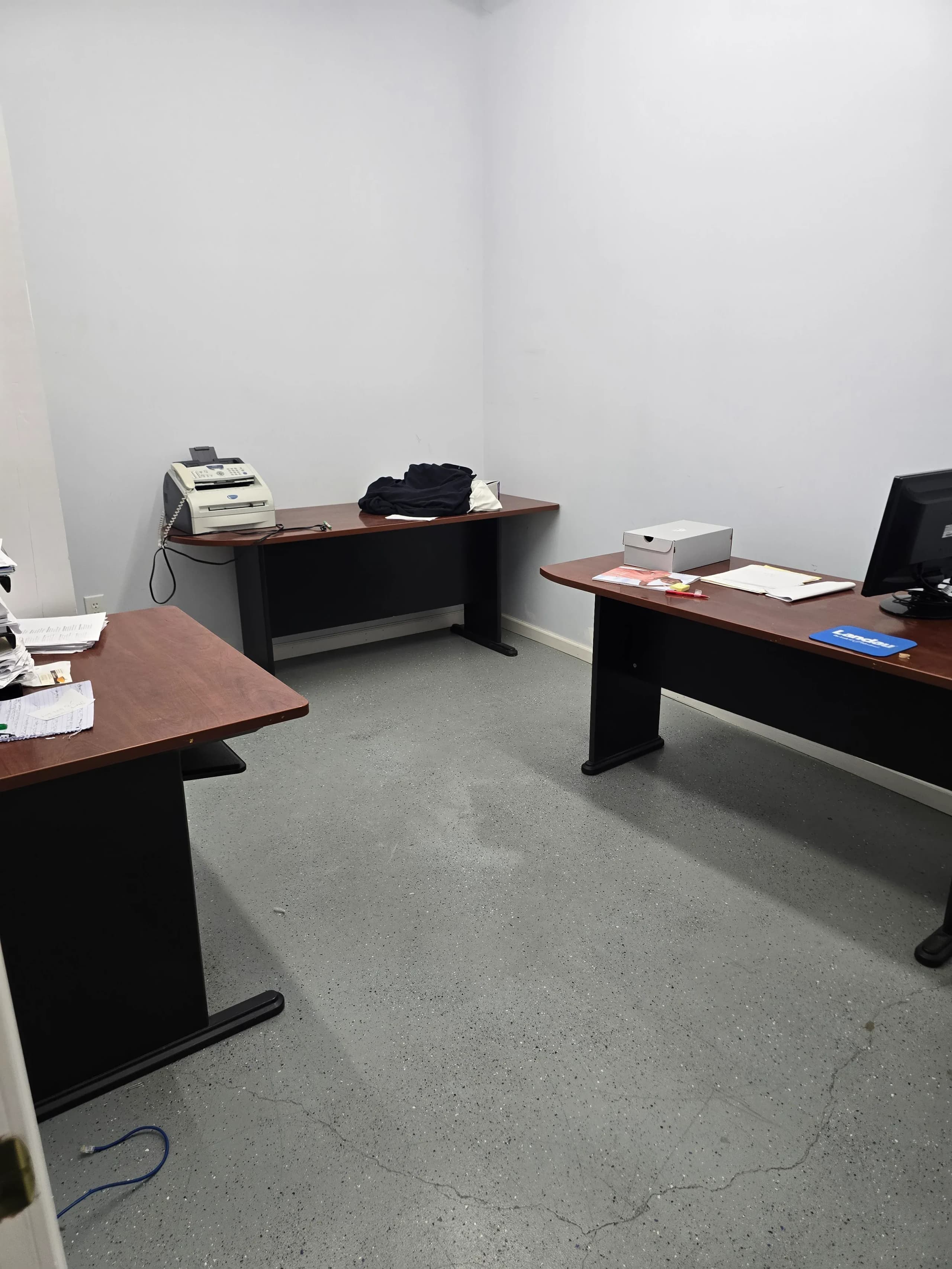 Three freestanding desks with monitors and a printer in a small commercial office