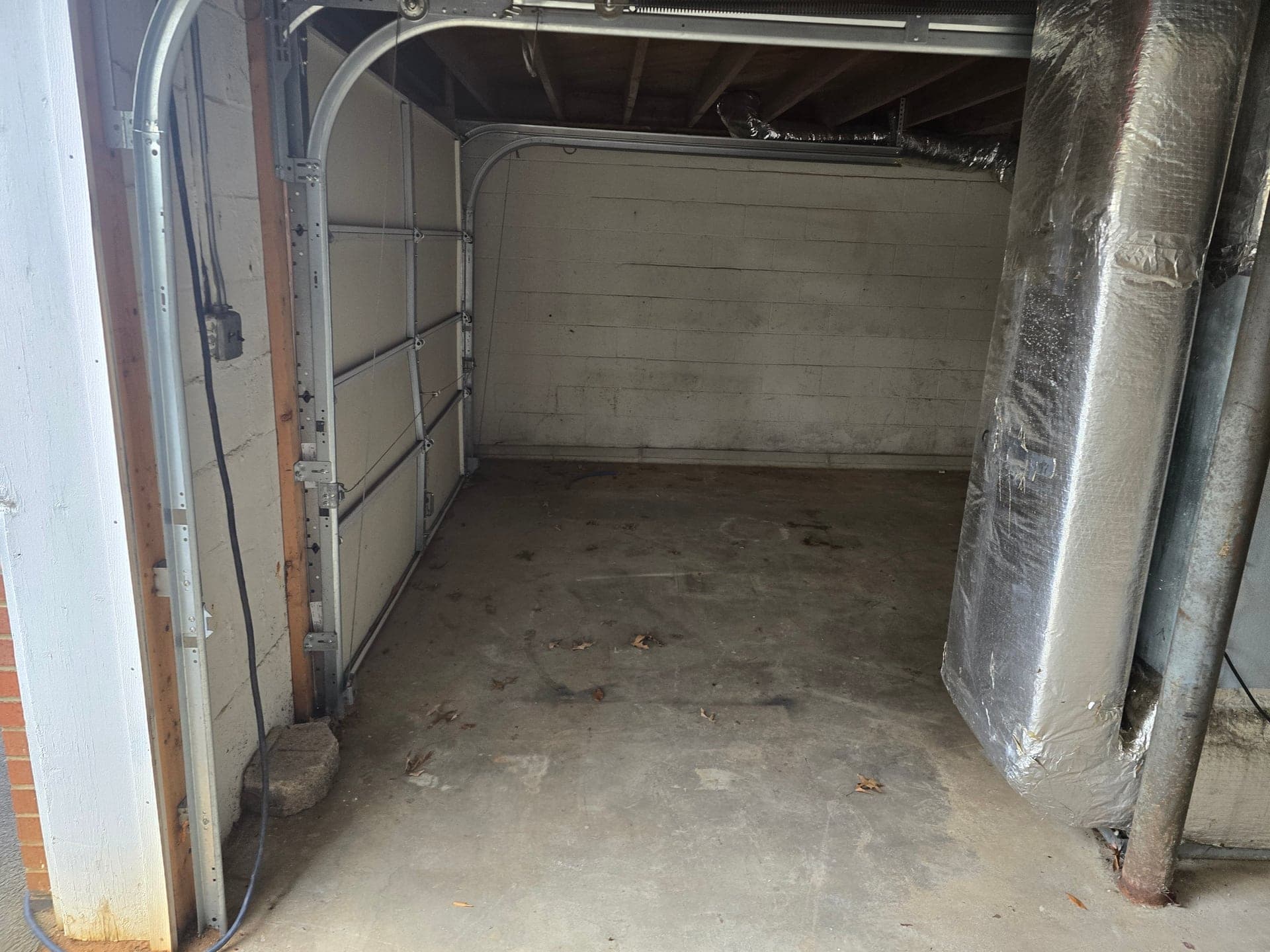 Empty garage corner with concrete floor and cinder-block wall after appliance removal