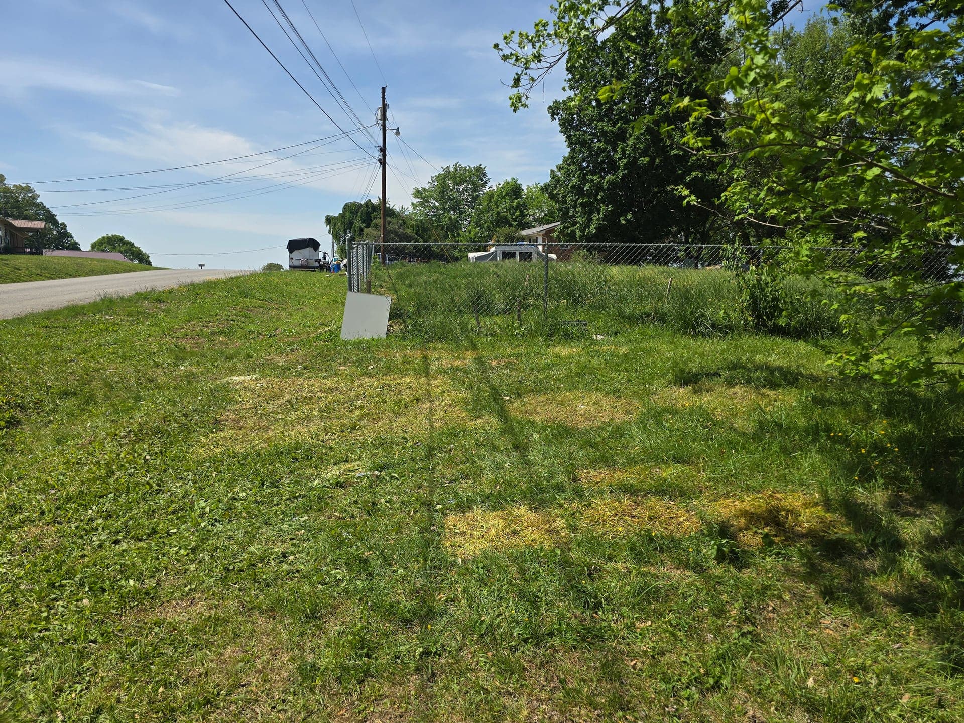 Cleared grassy lawn beside a chain-link fence after bulk appliance removal