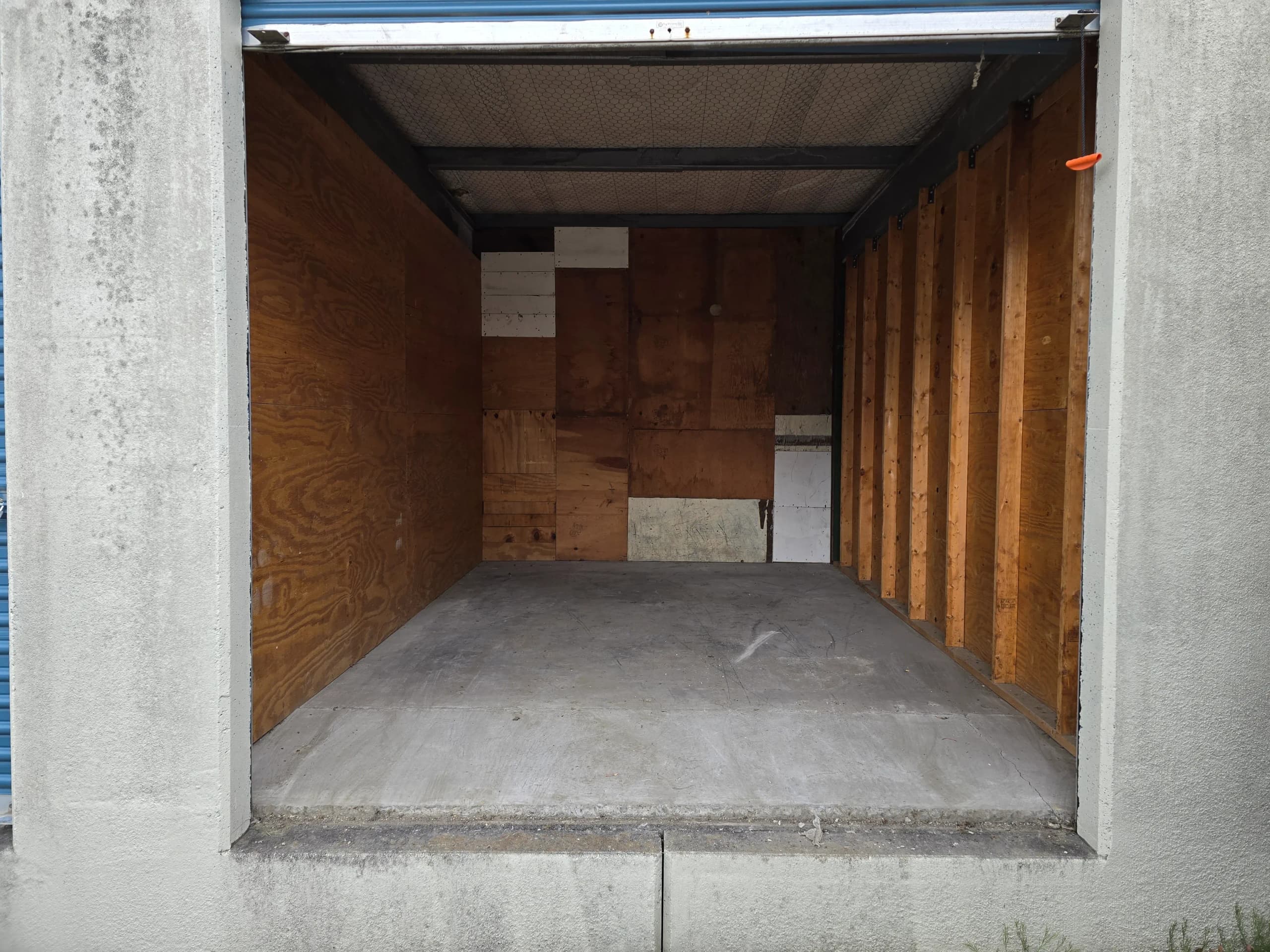 Empty storage unit with concrete floor and plywood walls after a cleanout