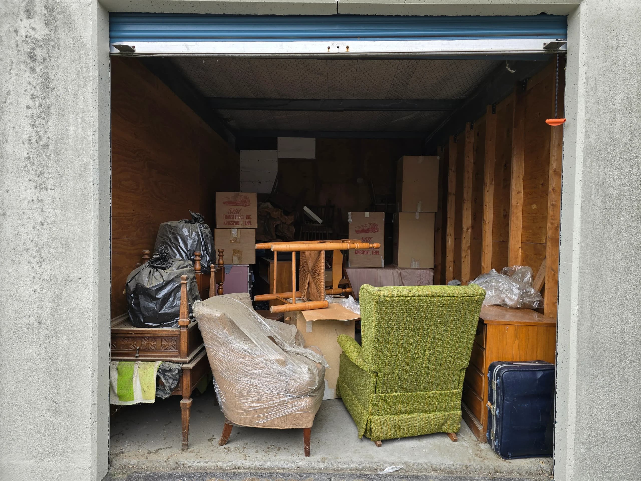 Storage unit packed with furniture, boxes, and bags before a cleanout