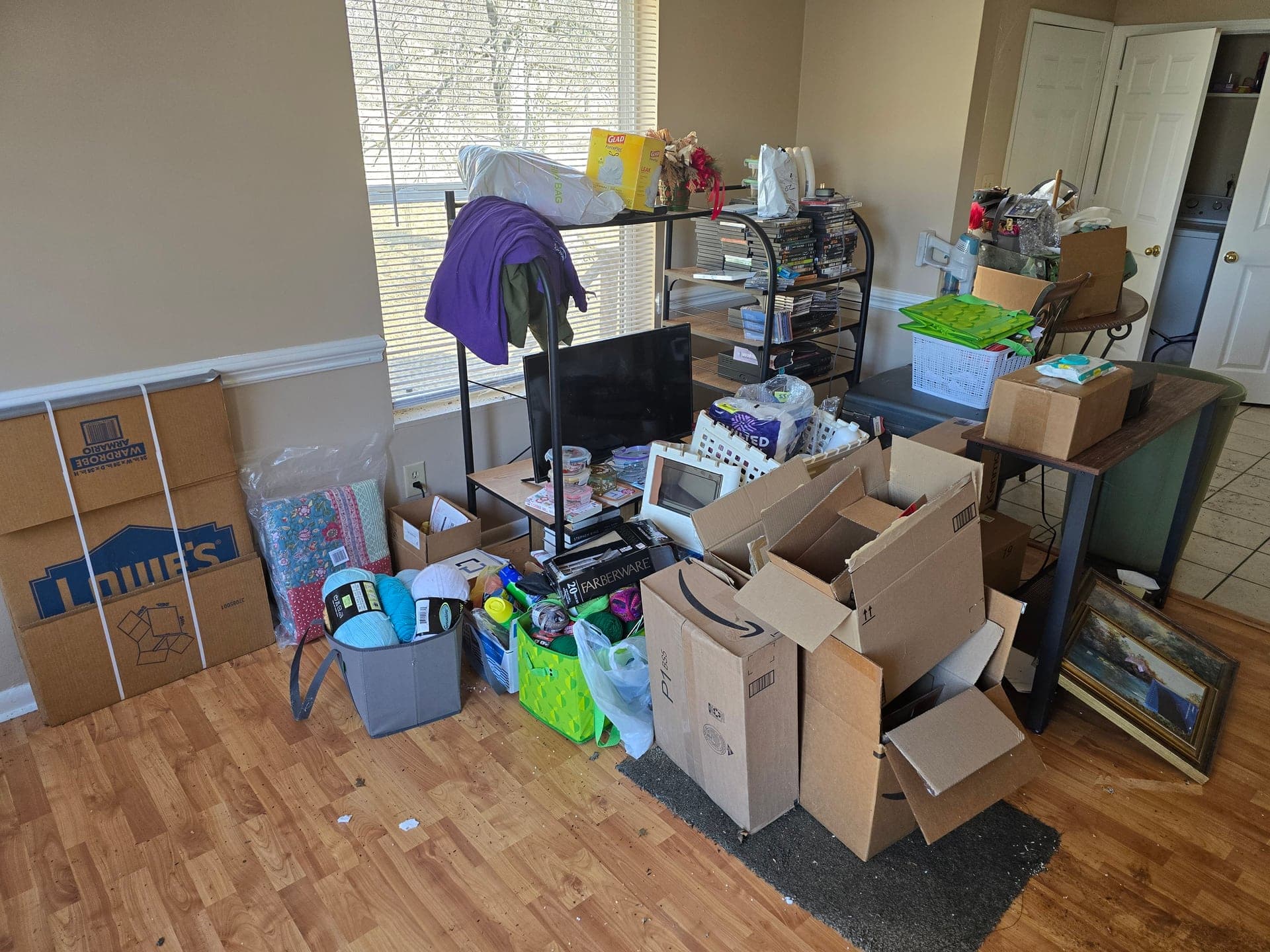 Cardboard boxes, bins, and personal belongings packed in a room during an estate cleanout