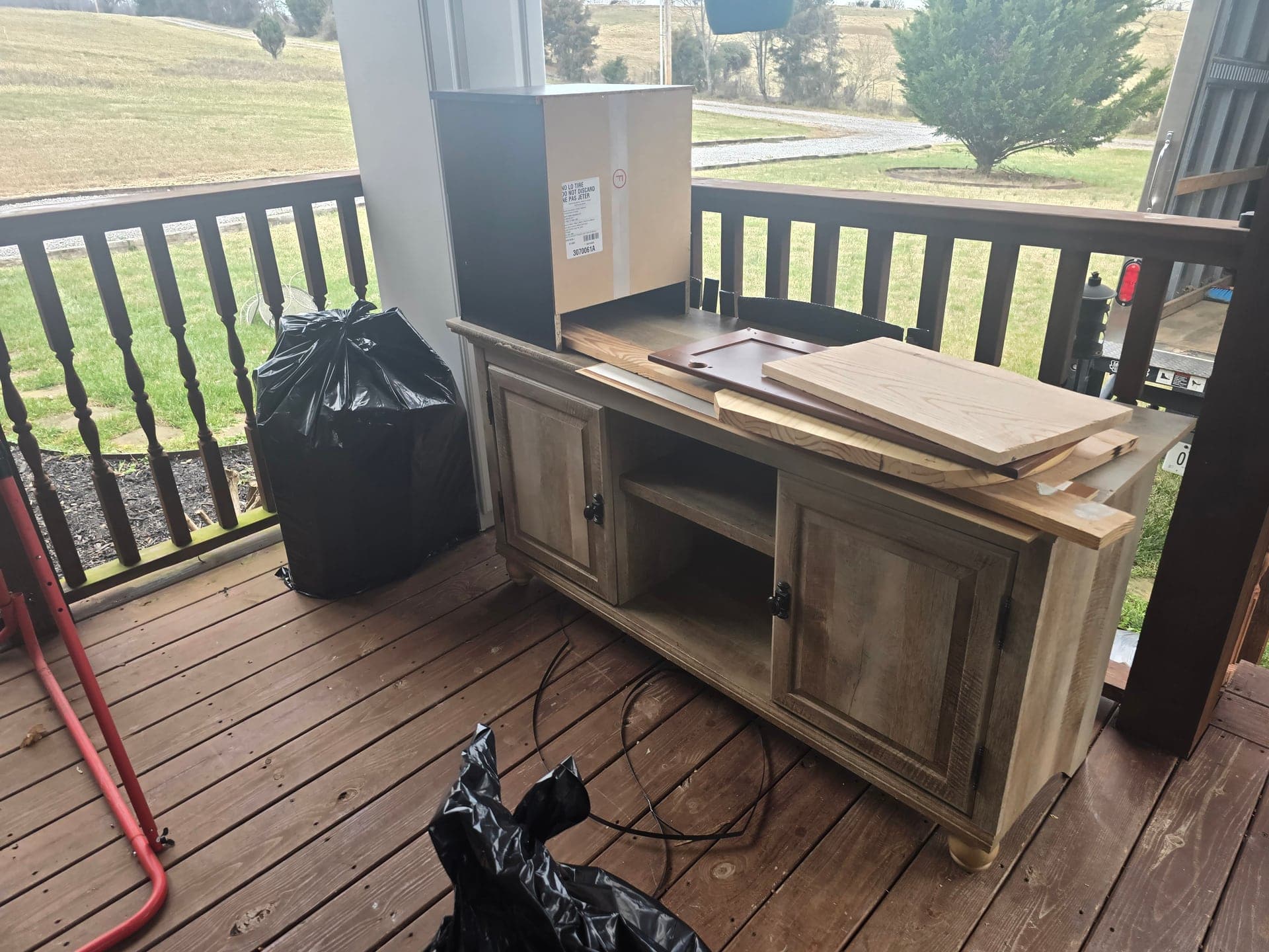 Wooden sideboard, boxes, and trash bags on a porch before an estate cleanout in Kingsport, TN