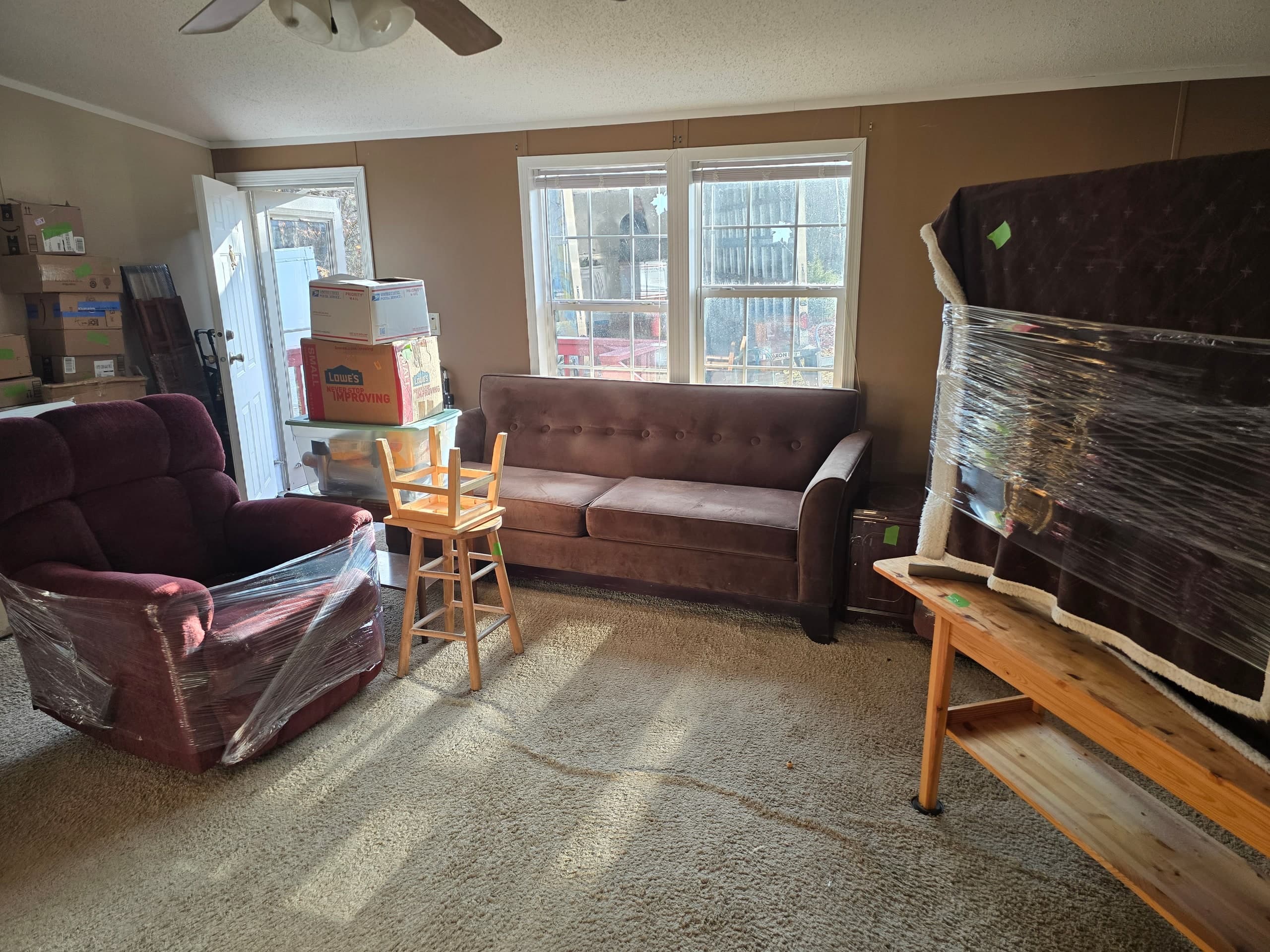 Wrapped furniture and moving boxes in a living room during an estate cleanout
