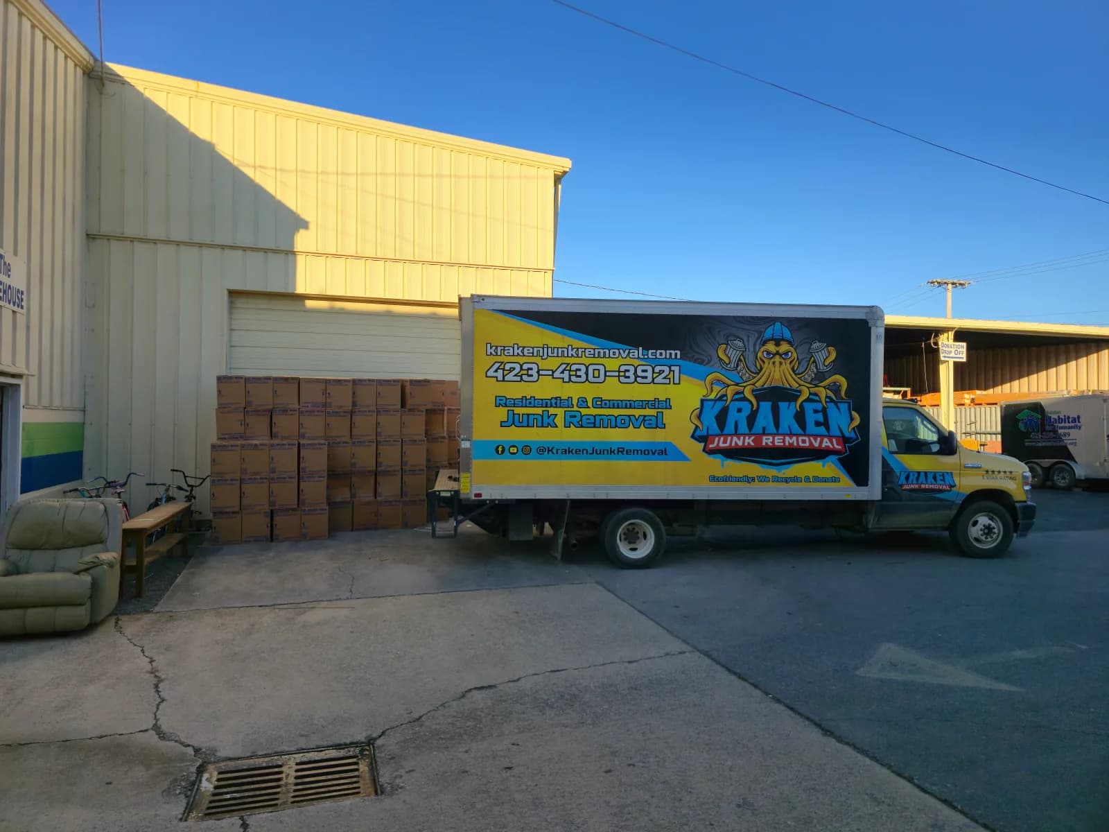 Kraken Junk Removal truck at a donation drop-off, with a Habitat for Humanity truck parked behind it. This photo is not a hoarding cleanout.