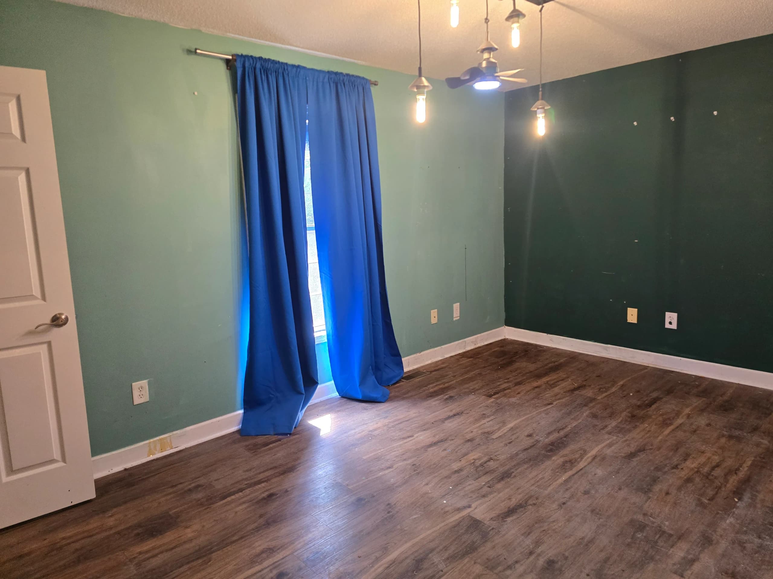 The same bedroom after the contents were removed, with blue curtains and the floor cleared