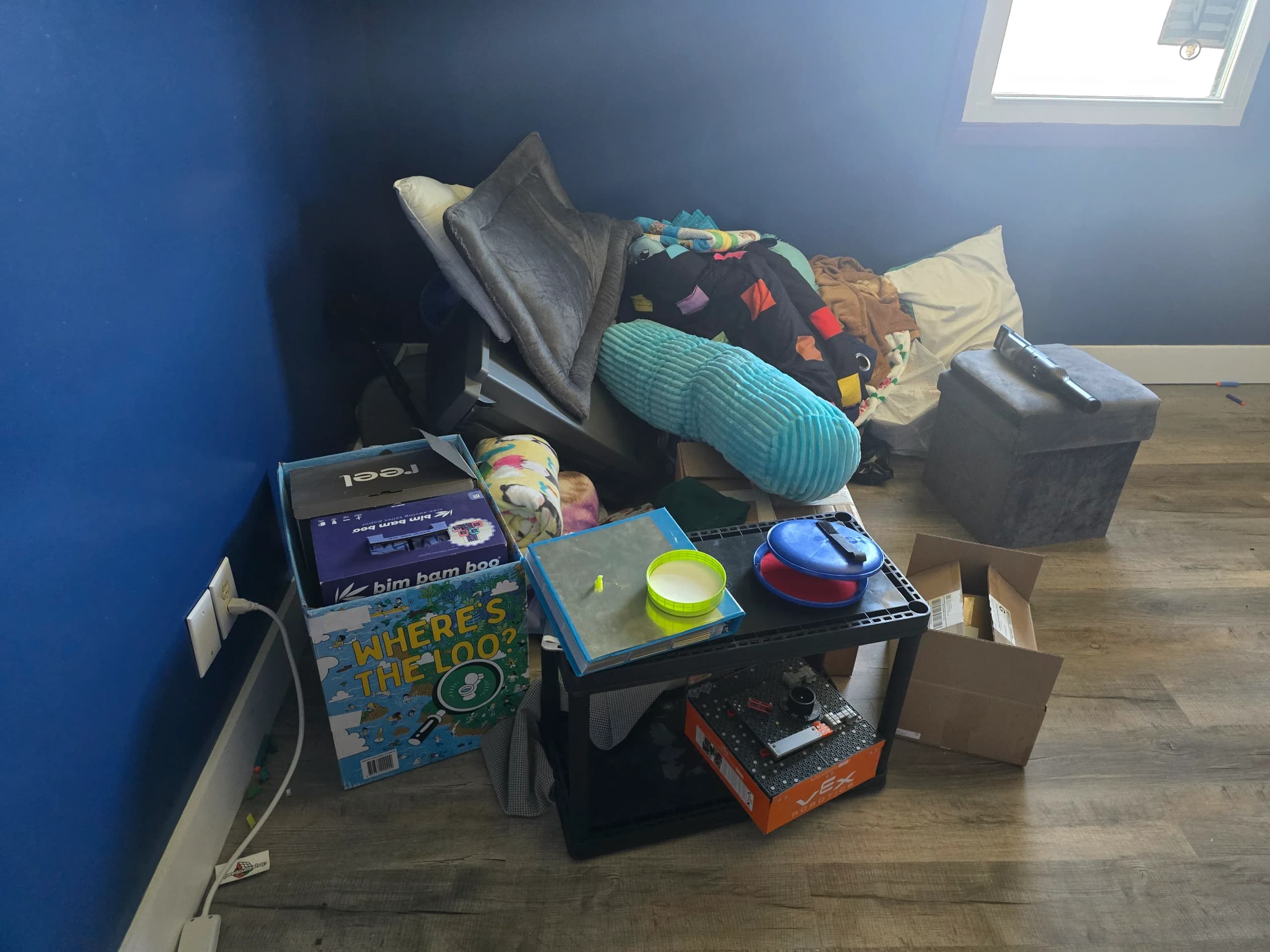 Corner piled with boxes, bedding, and household items before a house cleanout