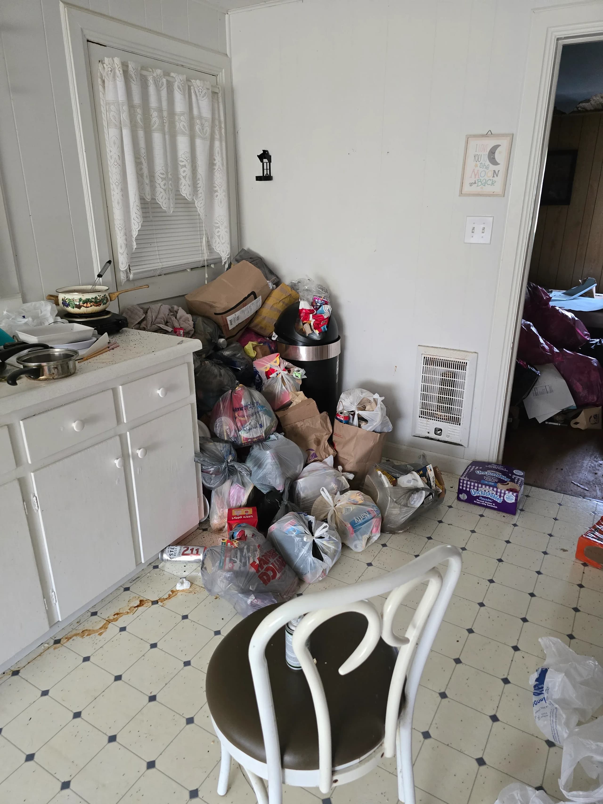 Kitchen filled with trash bags and clutter before a house cleanout