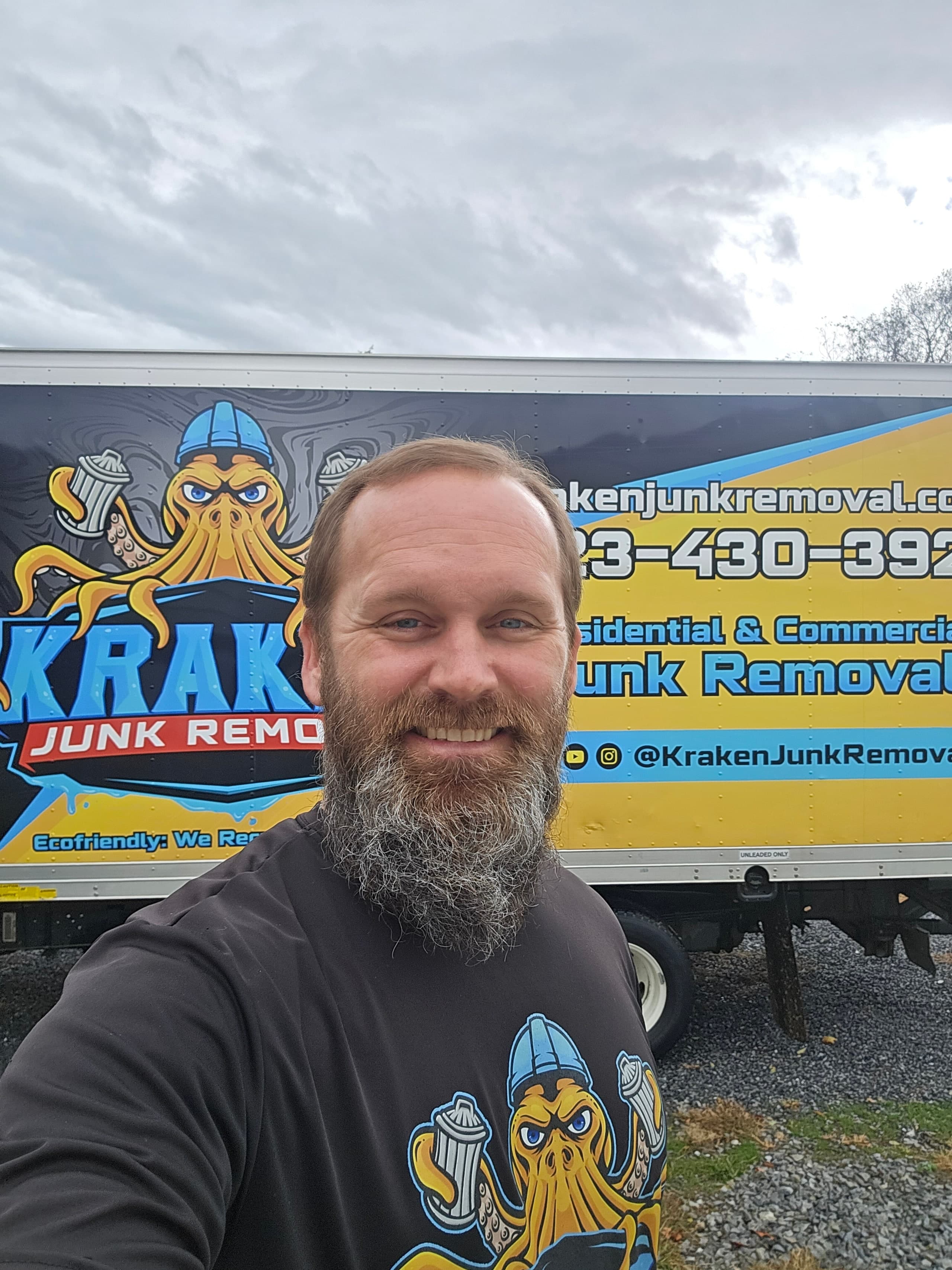 Kraken Junk Removal crew member standing in front of the branded company truck
