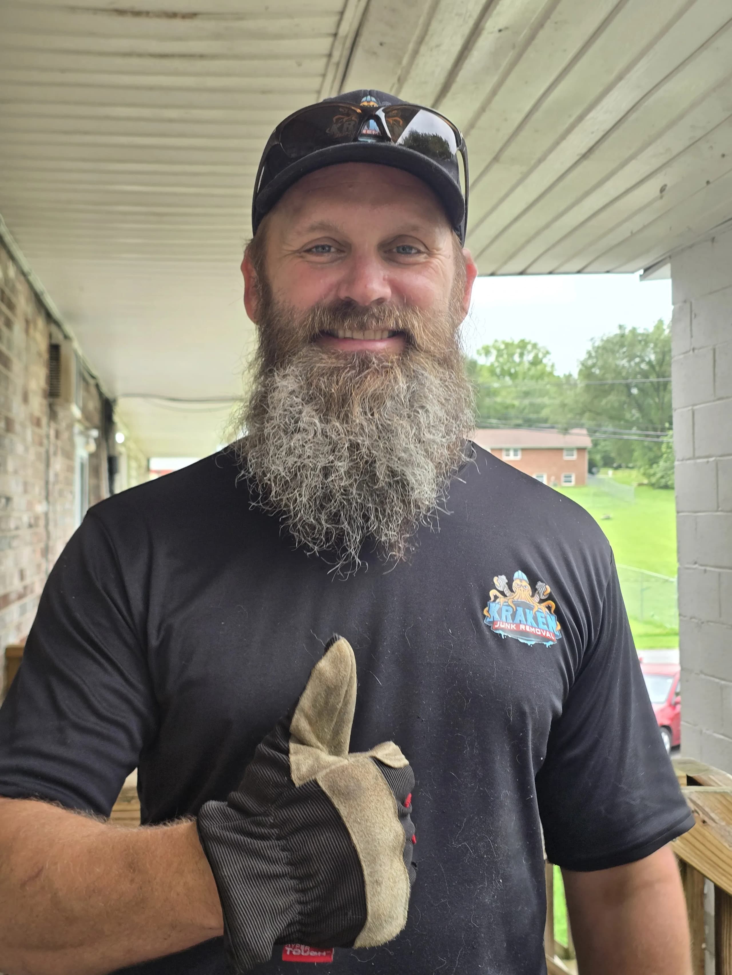 Austin, owner of Kraken Junk Removal, giving a thumbs-up in a branded company shirt
