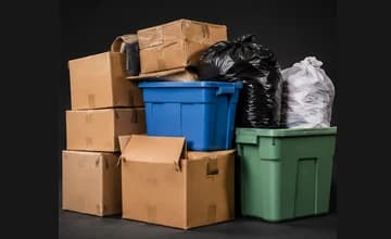 Stacked cardboard boxes, plastic storage totes, and tied bags