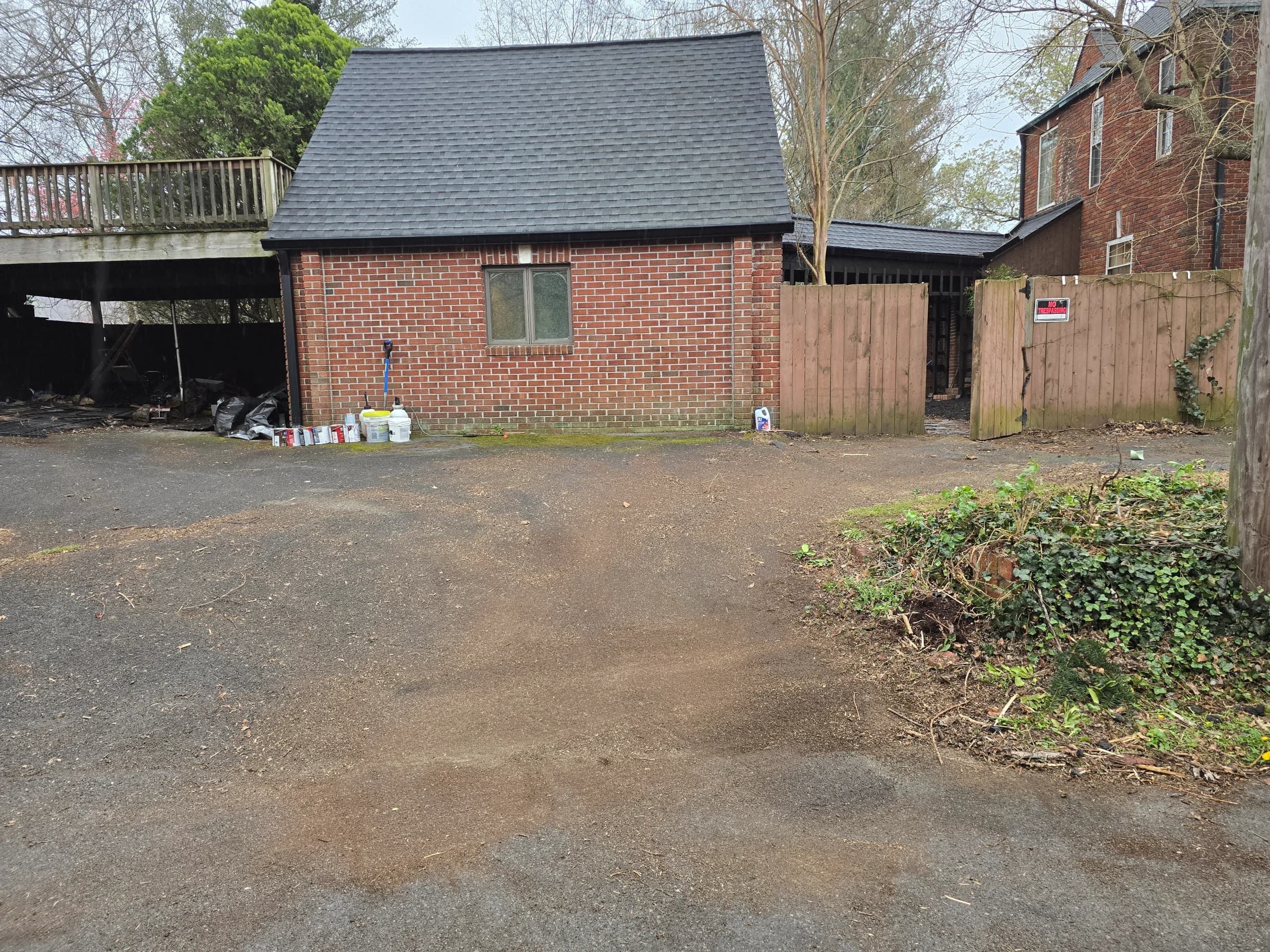 Cleared asphalt driveway in front of a brick outbuilding after yard waste removal