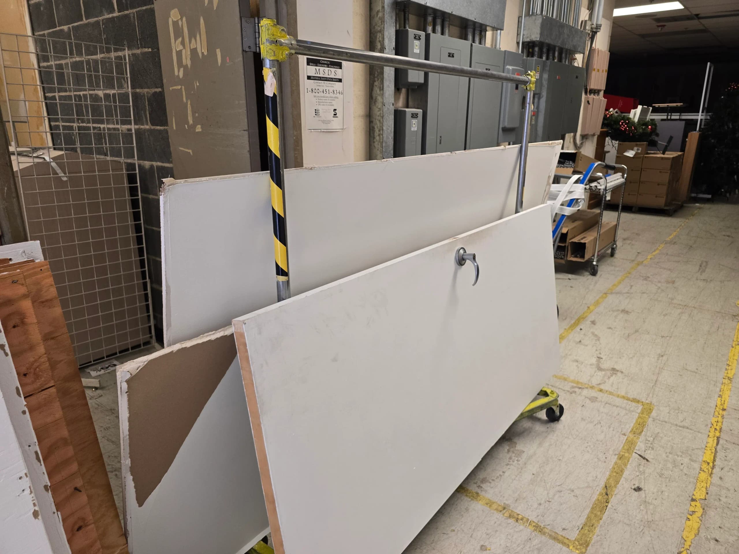 Commercial door and broken drywall panels stacked on a metal cart inside a warehouse cleanout