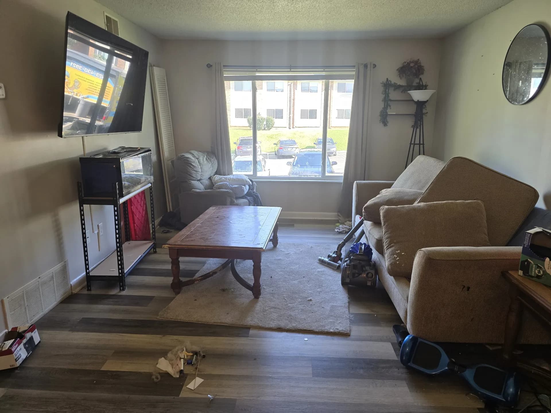 Living room with a sofa and coffee table looking out to a parking lot and apartment building