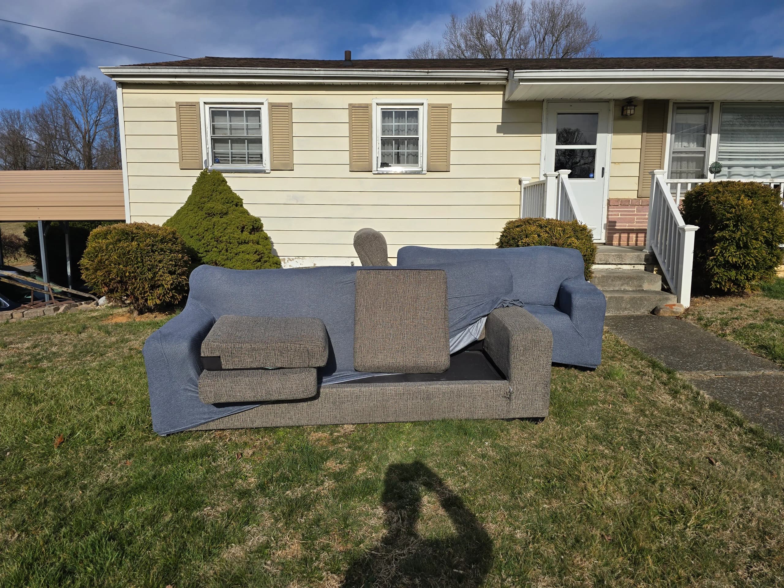 Two sofas sitting on a front lawn in front of a house, ready for furniture removal