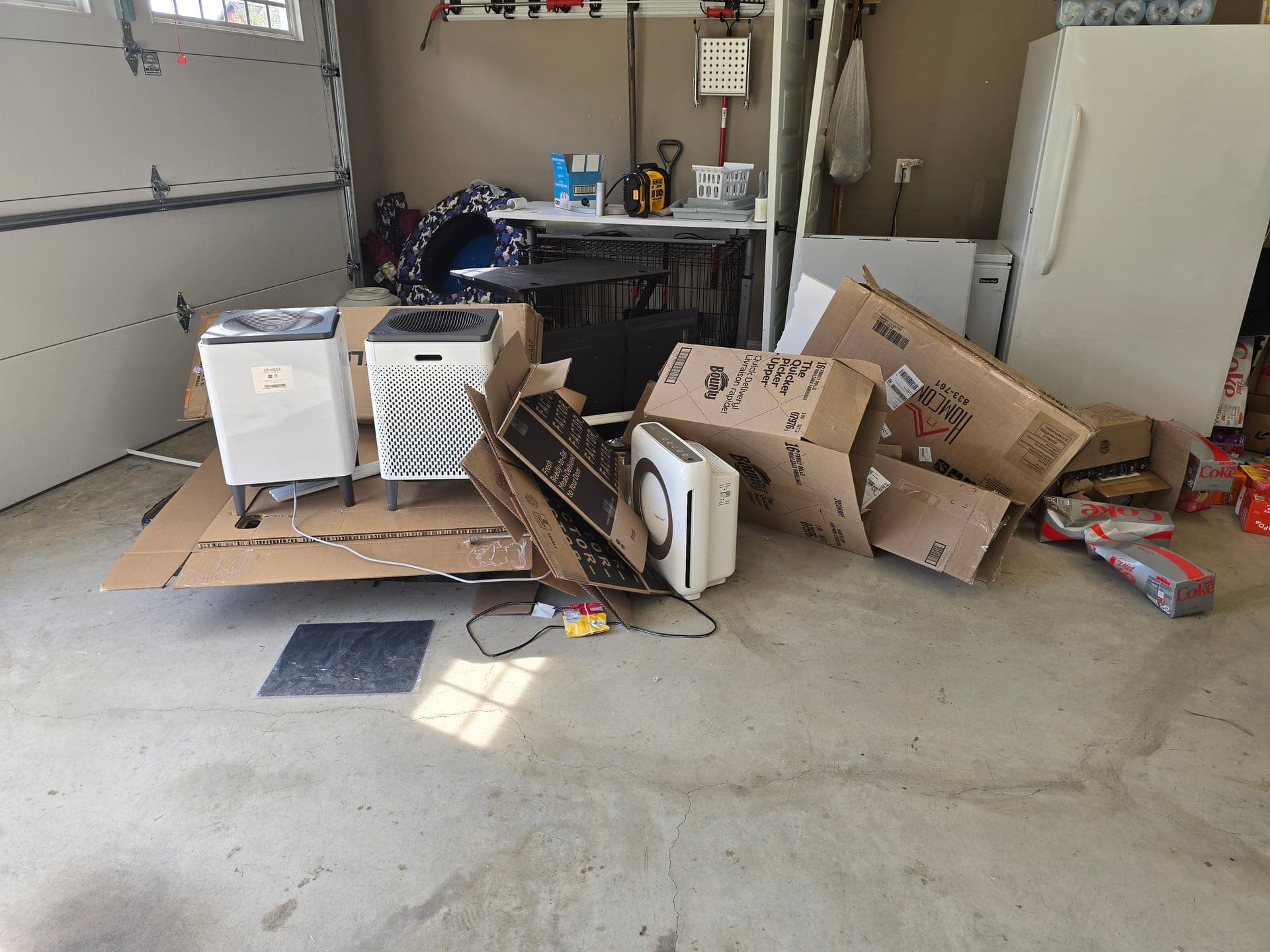 Cardboard boxes and household items piled on a garage floor during a cleanout