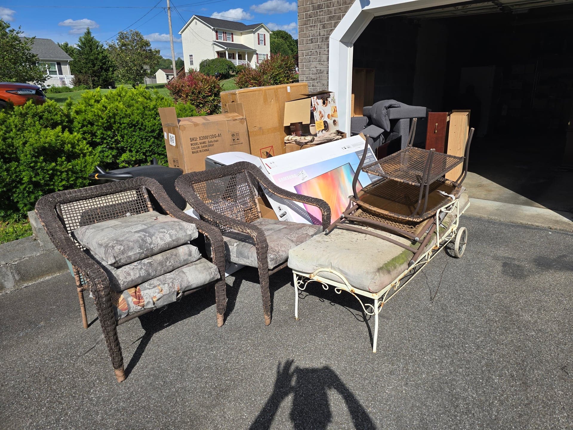 Old patio furniture and bulky items staged in a driveway during a garage cleanout