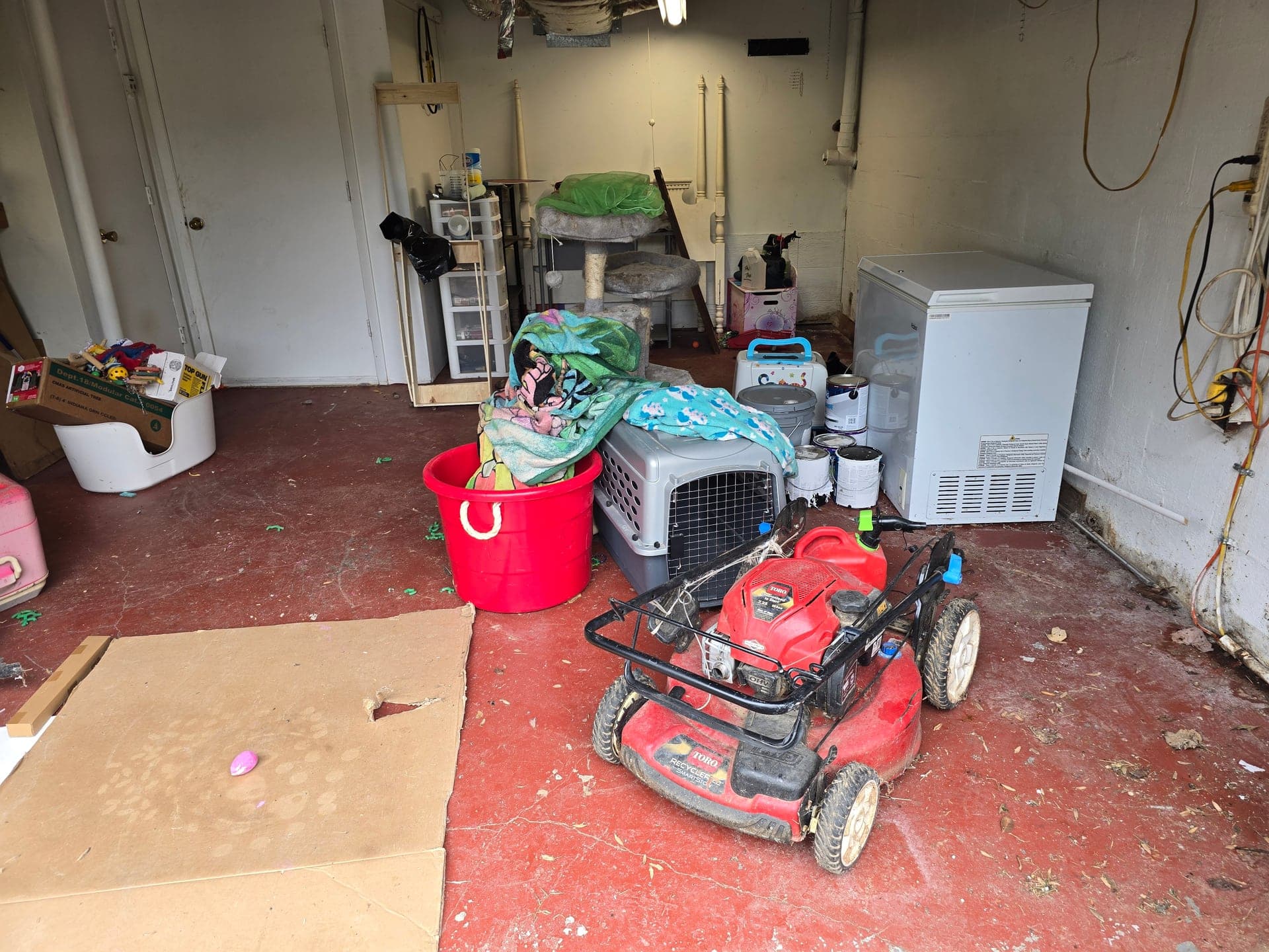 Lawn mower, freezer, and miscellaneous items cluttering a garage during a cleanout
