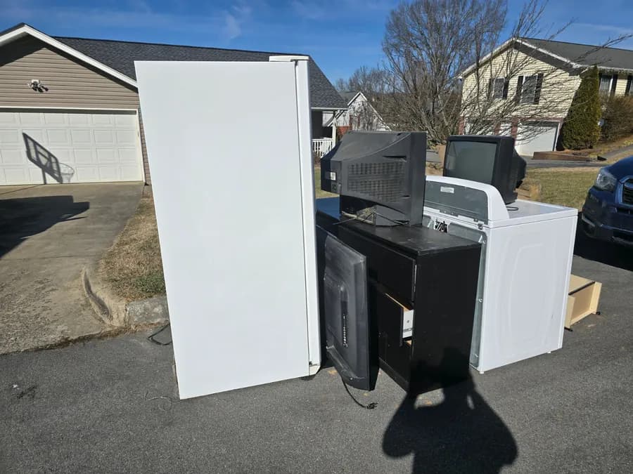 Household appliances ready for removal beside a Kraken Junk Removal truck