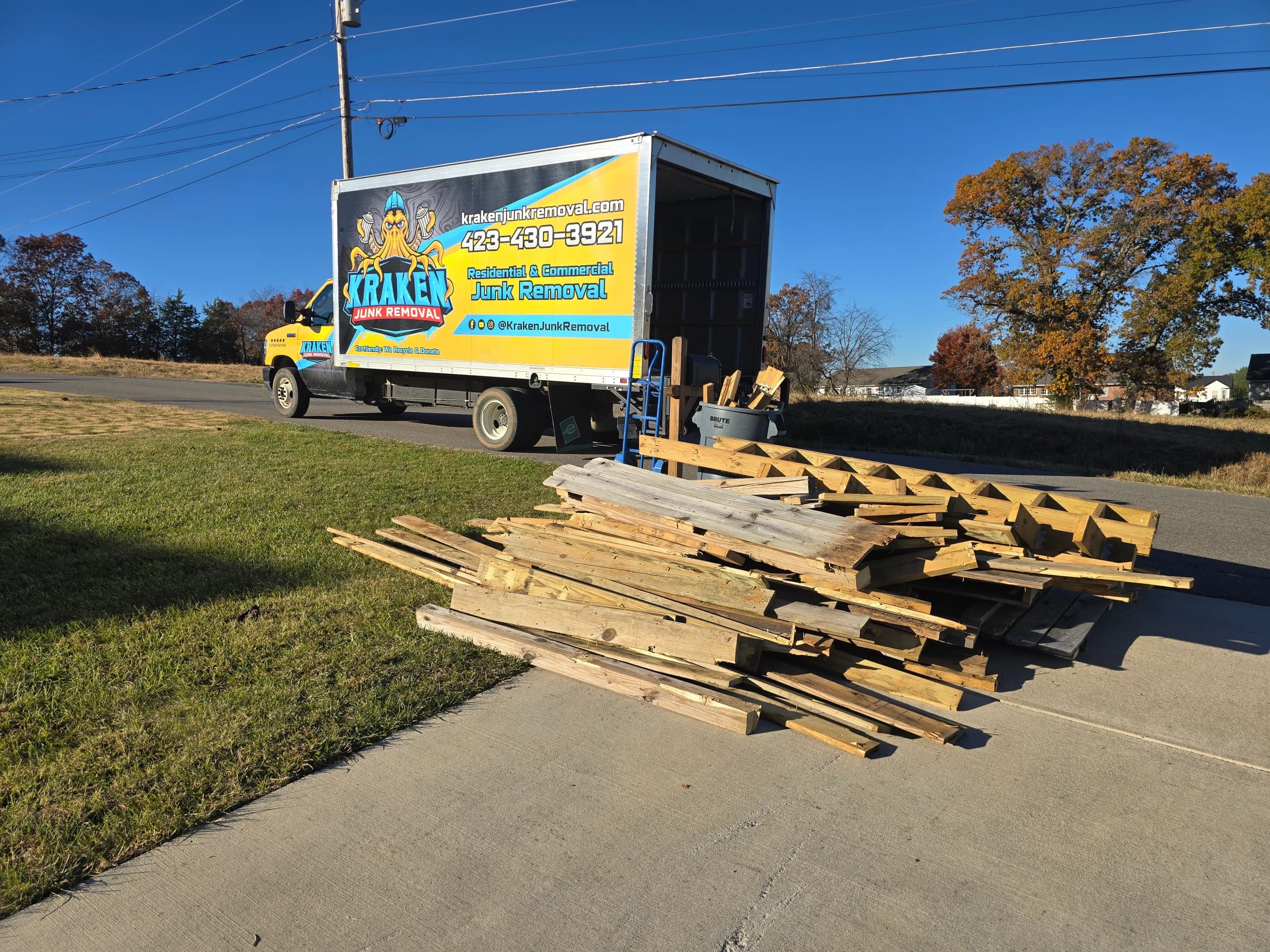 Construction debris staged for removal beside a Kraken Junk Removal truck