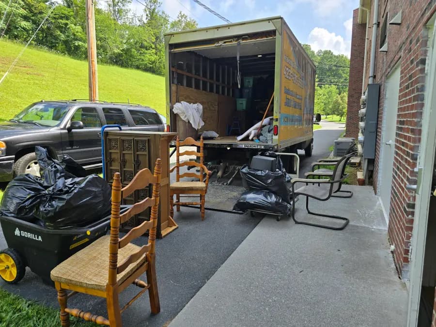 Kraken Junk Removal truck with wooden chairs and a cabinet staged for loading