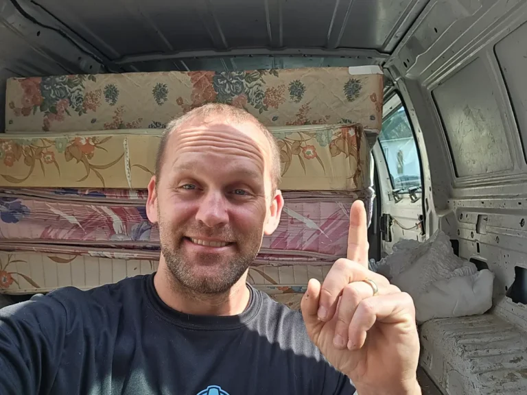 Smiling man pointing inside a truck loaded with mattresses during a junk removal job in Greeneville, TN.