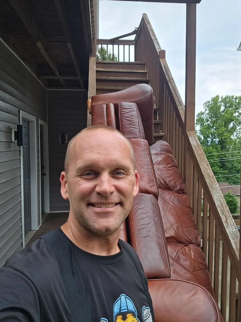 Kraken Junk Removal standing in front of a couch on stairs, showcasing furniture disposal near me Tri-Cities, TN.