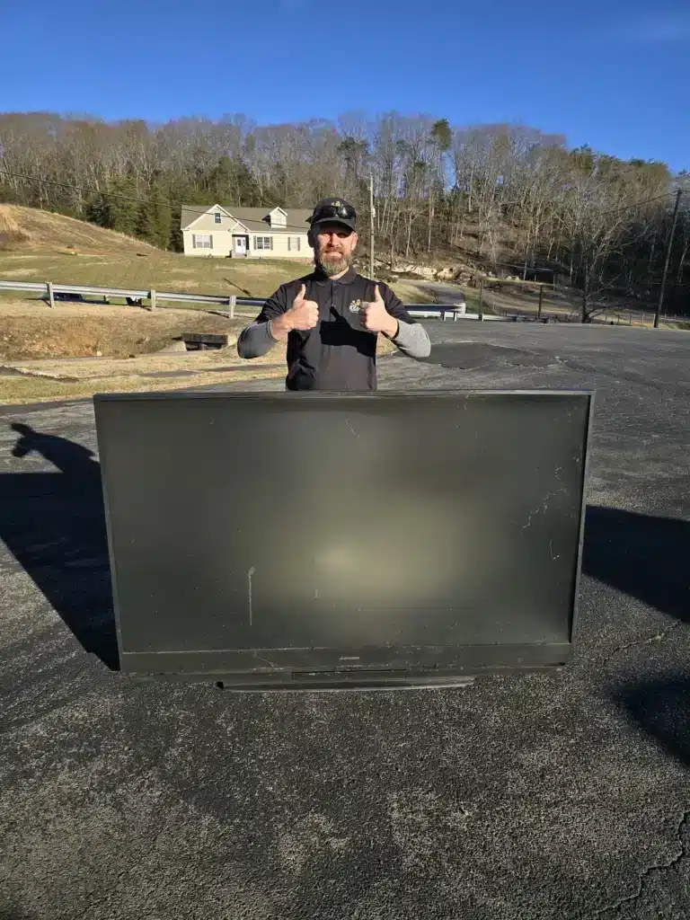 Owner of Kraken Junk Removal standing behind a large TV ready for recycling in Tri-Cities, TN.